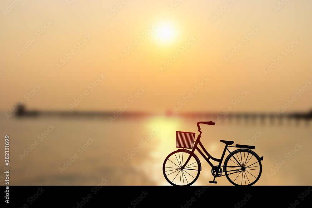 Fototapeta premium Silhouette women's style bike at sunset on seascape with bridge and cloud sky. Vector illustration design