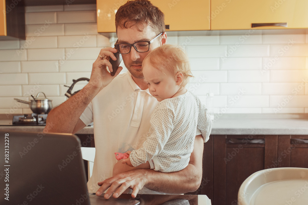 Happy young father working on laptop at home with little baby daughter. Multitasking. Happy young father working on laptop at home with little baby daughter. Multitasking.