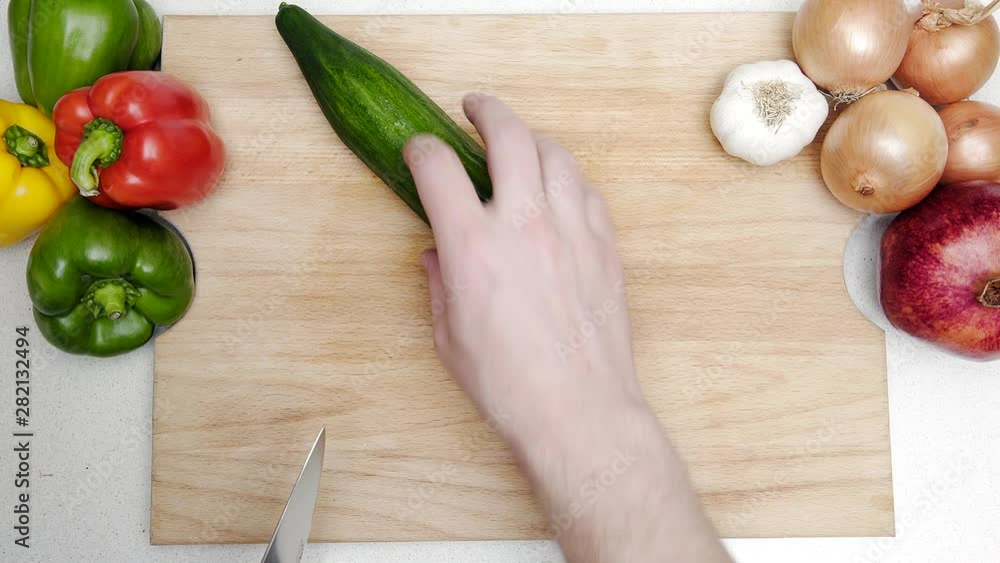 Top view shot of Caucasian hands chopping up a cucumber. Top view shot of Caucasian hands chopping up a cucumber.