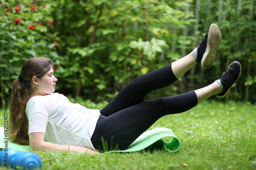 teenager girl lay exhausted on gym rag with dumbbell after train exercises photo