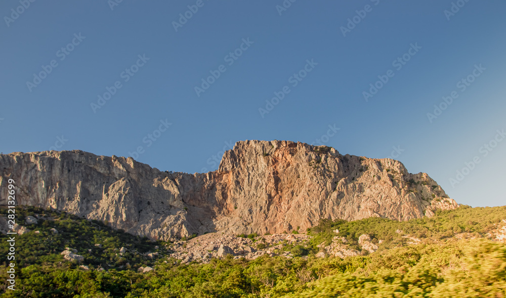 Obraz premium Russian mountains. Crimea. Summer mountains background. Forest and mountains in the sun on the background of a cloudy sky above the peninsula of Crimea. Sunny, bright, saturated raster photo