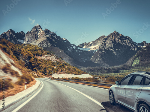White car on a mountain road. Highway among the mountain scenery. Toned photo.