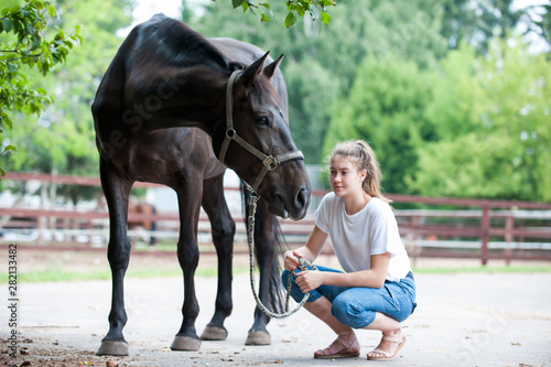 Black horse gazing away close to her owner - young teenage girl