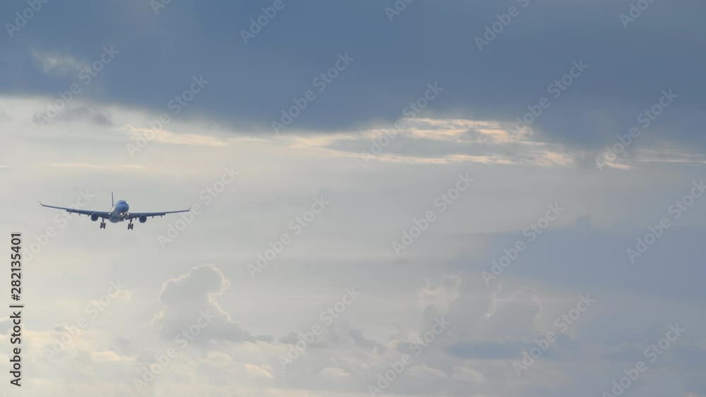 Close up of big jet airplane is landing in blue sunset sky with dark dramatic clouds filmed handheld Close up of big jet airplane is landing in blue sunset sky with dark dramatic clouds filmed handheld