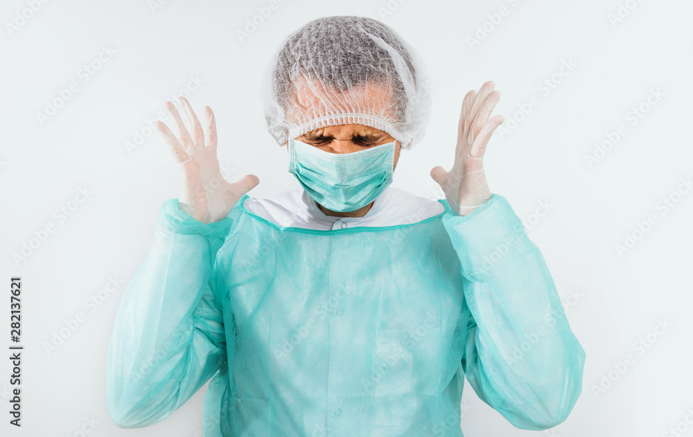 Angry and frustrated surgeon after surgery dressed in a green surgical apron and face mask on a light background. Medical and pharmaceutical concept. Failure of surgery, anger, medical errors. Angry and frustrated surgeon after surgery dressed in a green surgical apron and face mask on a light background. Medical and pharmaceutical concept. Failure of surgery, anger, medical errors.