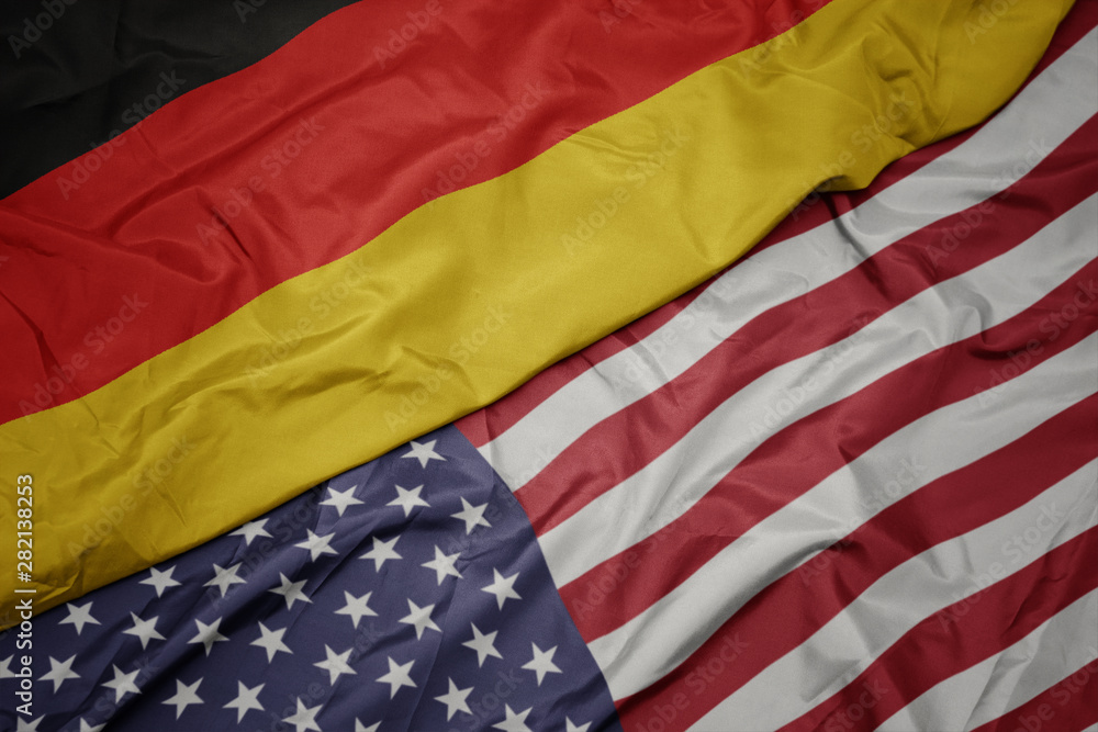 Obraz premium waving colorful flag of united states of america and national flag of germany. macro