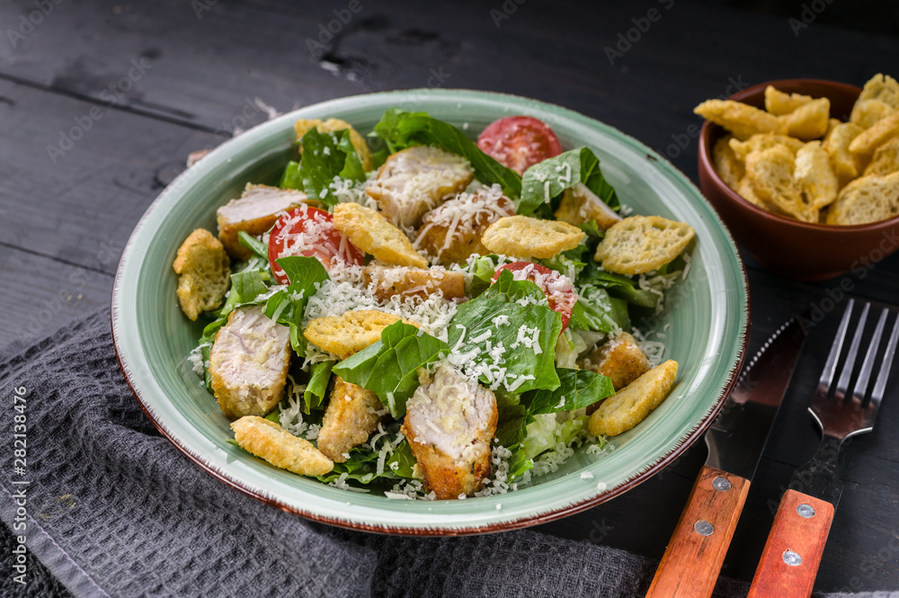 Close-up Caesar salad with fried chicken, parmesan and croutons on a dark rustic background. Horizontal shot Close-up Caesar salad with fried chicken, parmesan and croutons on a dark rustic background. Horizontal shot