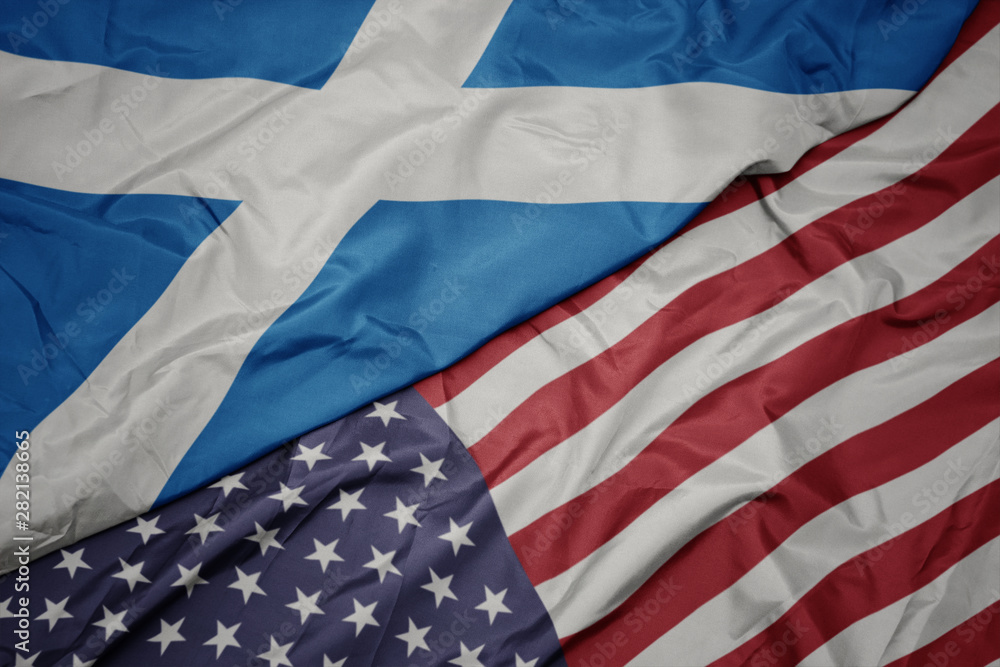 Obraz premium waving colorful flag of united states of america and national flag of scotland. macro