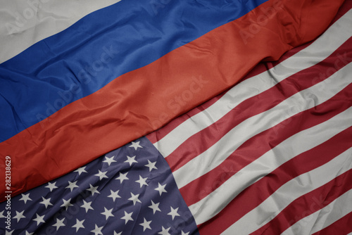 waving colorful flag of united states of america and national flag of russia. macro