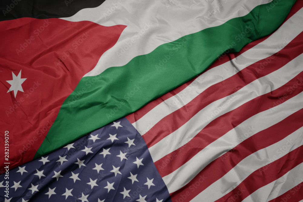 Obraz premium waving colorful flag of united states of america and national flag of jordan.