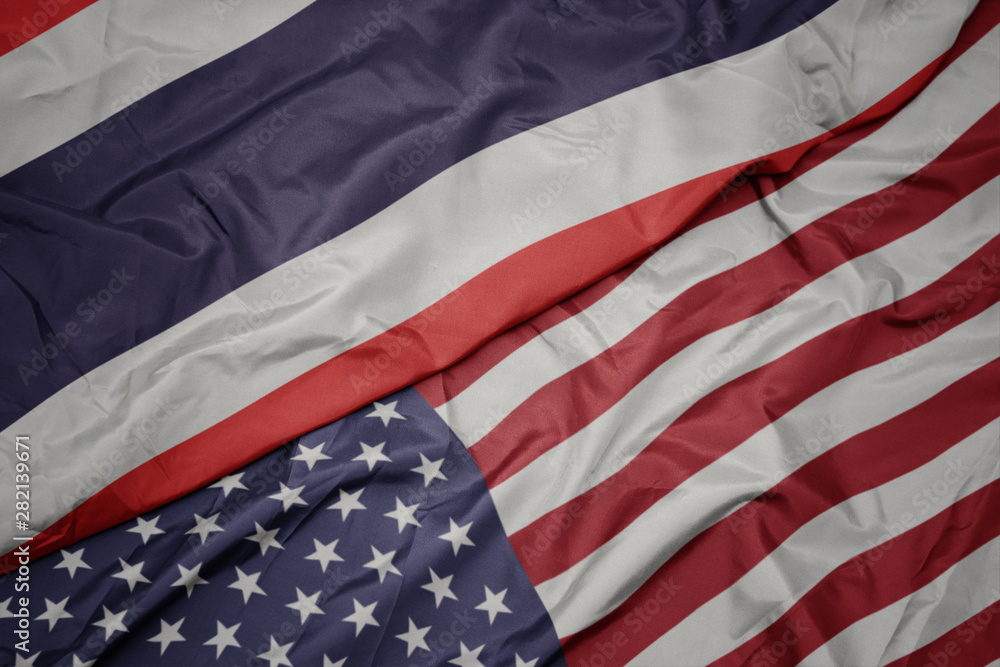 Obraz premium waving colorful flag of united states of america and national flag of thailand.