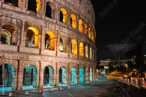 Colosseum building at night - illuminated with yellow and blue colors. (European Union flag colors).