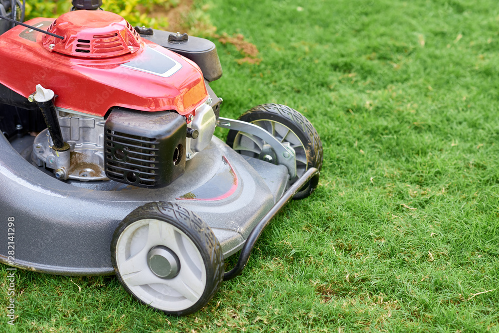 Lawn mover on green grass in a garden close up Lawn mover on green grass in a garden close up