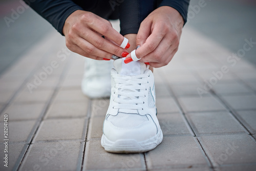 Woman get ready for run. Female hands tying shoelaces on a sport sneakers