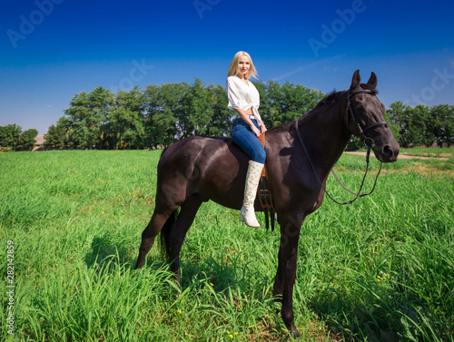 Woman and horse, green field, white blouse and jeans