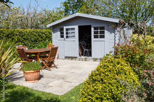 Canvas Print Shed with open door and terrace with wooden garden furniture during spring