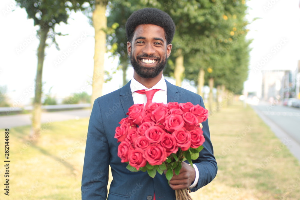 Beautiful happy man outside in the park with roses Beautiful happy man outside in the park with roses