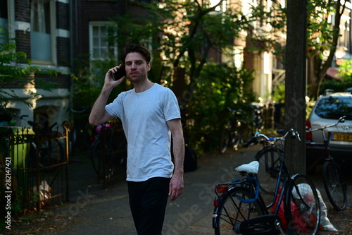 Canvas Print Dutch student talking on his phone while walking in front of his student house i