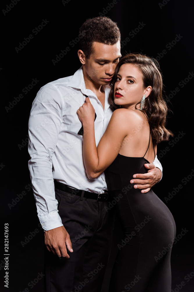 beautiful young woman hugging handsome mixed race man isolated on black beautiful young woman hugging handsome mixed race man isolated on black