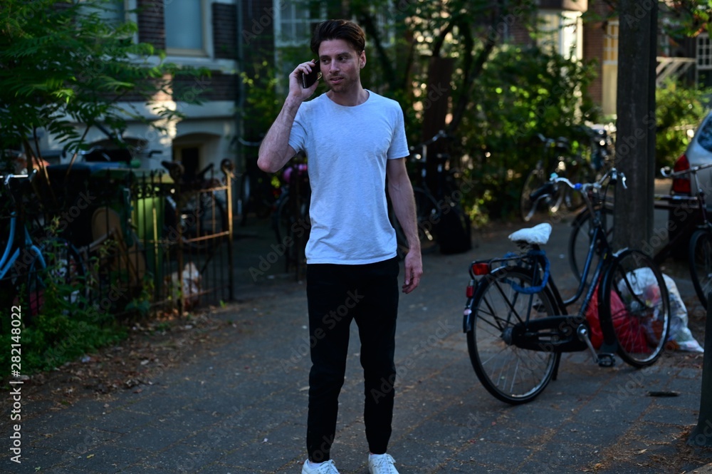 Dutch student talking on his phone while standing in front of his student house