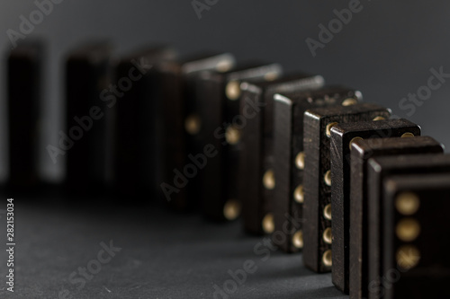 Domino effect, black domino tiles, on a black background. Game of the domino.