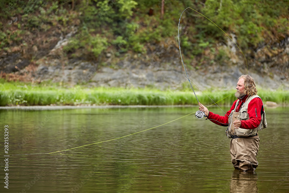 Flyfishing in waterproof clothing in river. Flyfishing in waterproof clothing in river.