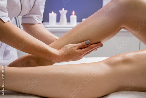 Beautiful young woman enjoying legs massage with oil in spa salon. Cosmetology