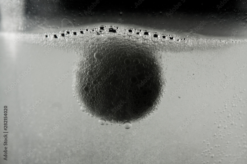 White medication tablet dissolving in a glass filled with water. Act on a black background. White medication tablet dissolving in a glass filled with water. Act on a black background.