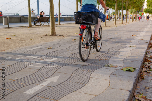 Close up view at bicycle lane symbol and cyclist ride bicycle on promenade riverside of Rhein River in Düsseldorf, Germany. Cycling friendly city in europe. Eco friendly mobility transportation.