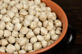 Raw chickpeas in a ceramic bowl on a dark wooden background. top view, out of range.