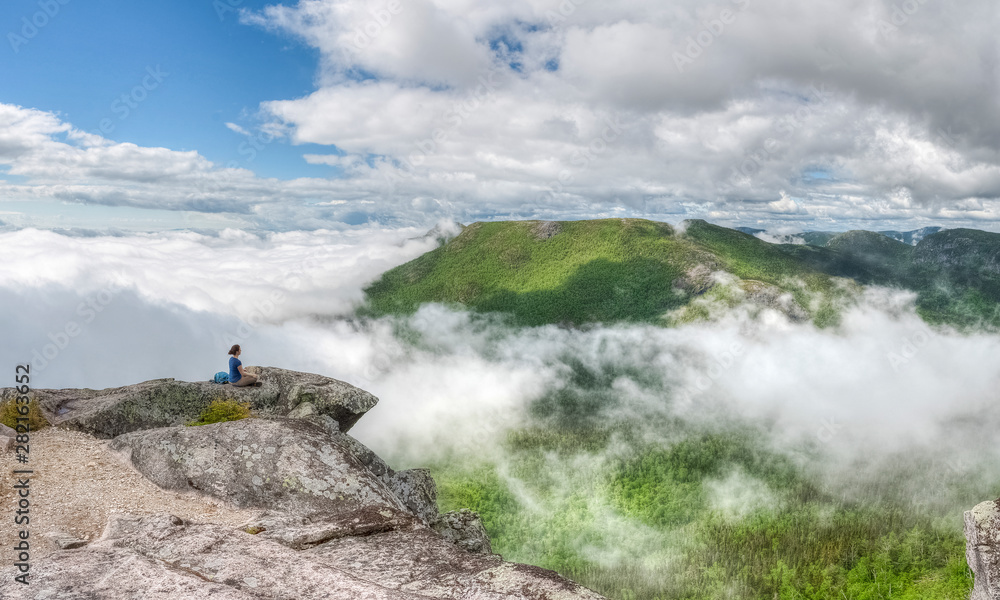 Meditating woman above the clouds, on the edge, healthy lifestyle