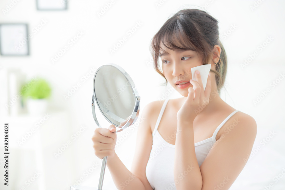 Beautiful young asian woman smile and joy with skin care use oil blotting paper on face looking mirror in the room, beauty asia girl happy and cheer makeup and cosmetic, health care on facial concept. Beautiful young asian woman smile and joy with skin care use oil blotting paper on face looking mirror in the room, beauty asia girl happy and cheer makeup and cosmetic, health care on facial concept.