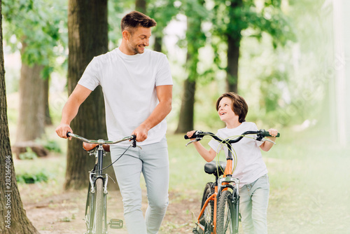 selective focus of father and son with bicycles looking at each other