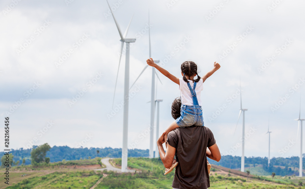 Father and daughter having fun to play together. Asian child girl riding on father's shoulders in the wind turbine field Father and daughter having fun to play together. Asian child girl riding on father's shoulders in the wind turbine field