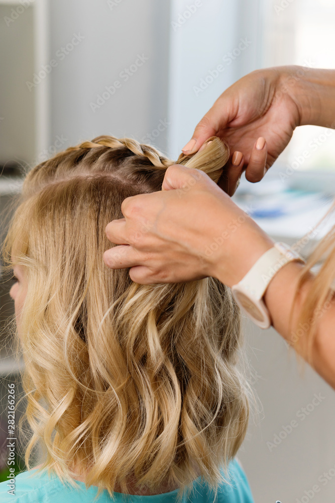 Fototapeta premium Barber braids high braid. Hairdressing services. Creating evening hairstyles fashionable stylish women's hairstyles. Process of hair styling. Courses in hairdressing. Beauty salon concept.