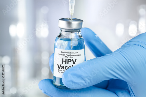 Healthcare concept with a hand in blue medical gloves holding HPV, human papillomavirus, vaccine vial photo