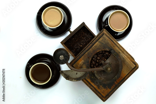 Different colored cups of coffee with a vintage coffee grinder on a white background. View from above flat lay.