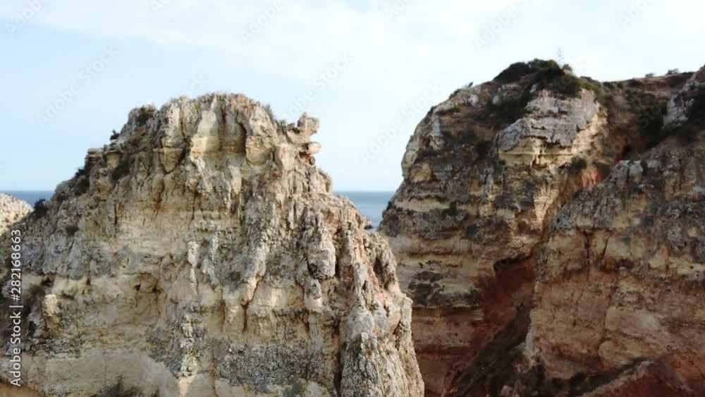Rising up over limestone rock formations in Algarve, Portugal to reveal boats and sea cliffs, Aerial. Rising up over limestone rock formations in Algarve, Portugal to reveal boats and sea cliffs, Aerial.