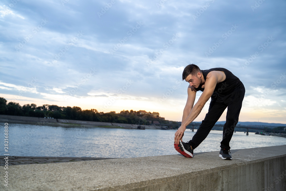 Young man stretching legs before run outdoors Young man stretching legs before run outdoors