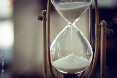 Closeup of white sugar inside hourglass. Vintage color tone