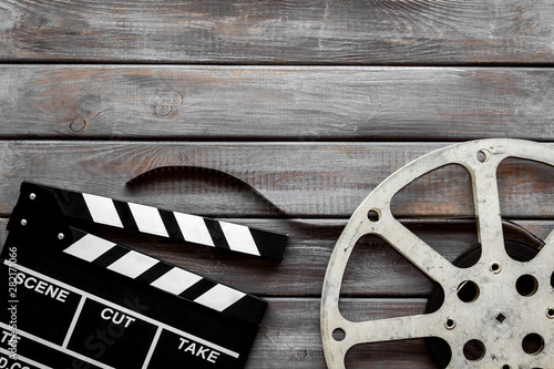 Filmmaker profession with clapperboard and video tape on wooden background top view copyspace
