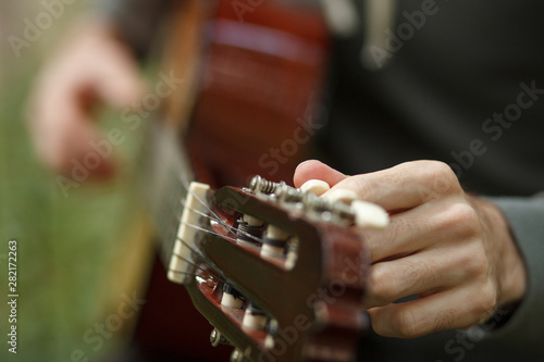 male hands tune acoustic guitar, close up detail photo, selective focus
