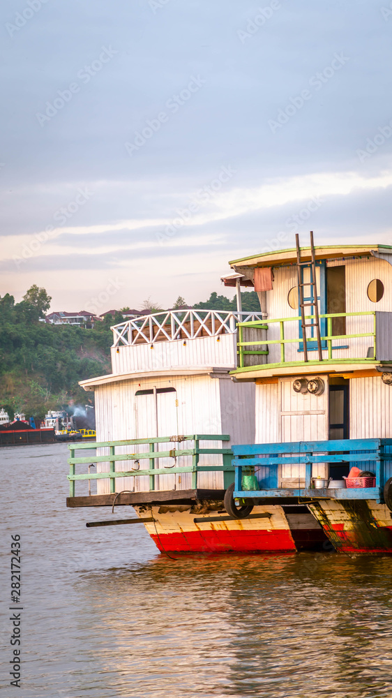 the activity of Mahakam river. tugboat dragging barge of coal and wooden boat which take passenger to the remote area of upper Mahakam, Borneo, Indonesia
