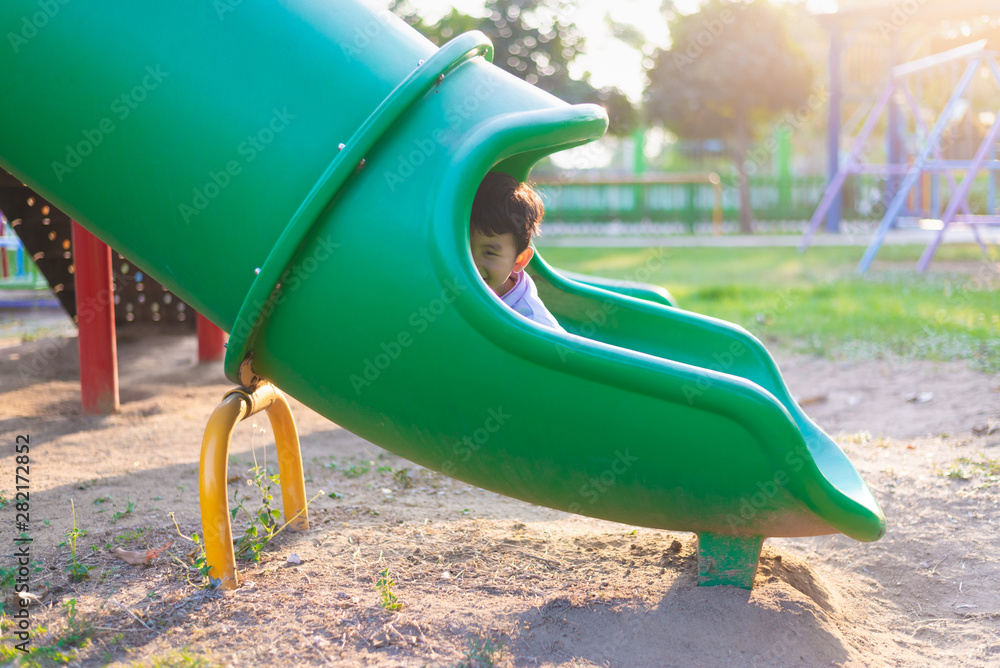 Asian kid playing slide at the playground under the sunlight in summer, Happy kid in kindergarten. Asian kid playing slide at the playground under the sunlight in summer, Happy kid in kindergarten.
