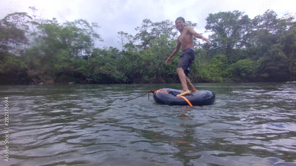 Indigenous Young Boy Playing Trying To Balance Over A River Inner Tube