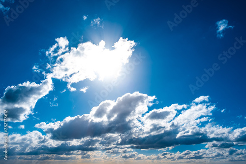 Blue sky with sun shining through white clouds background overlay