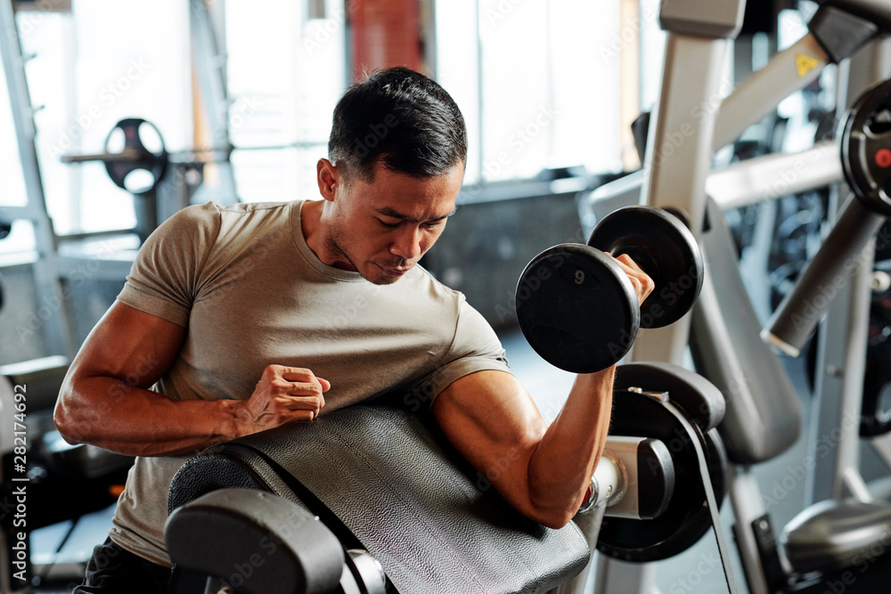 Fototapeta premium Fit serious Asian sportsman exercising with weights in gym