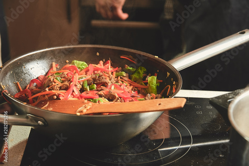 Juicy wok noodles lies in a pan in a large loft kitchen.