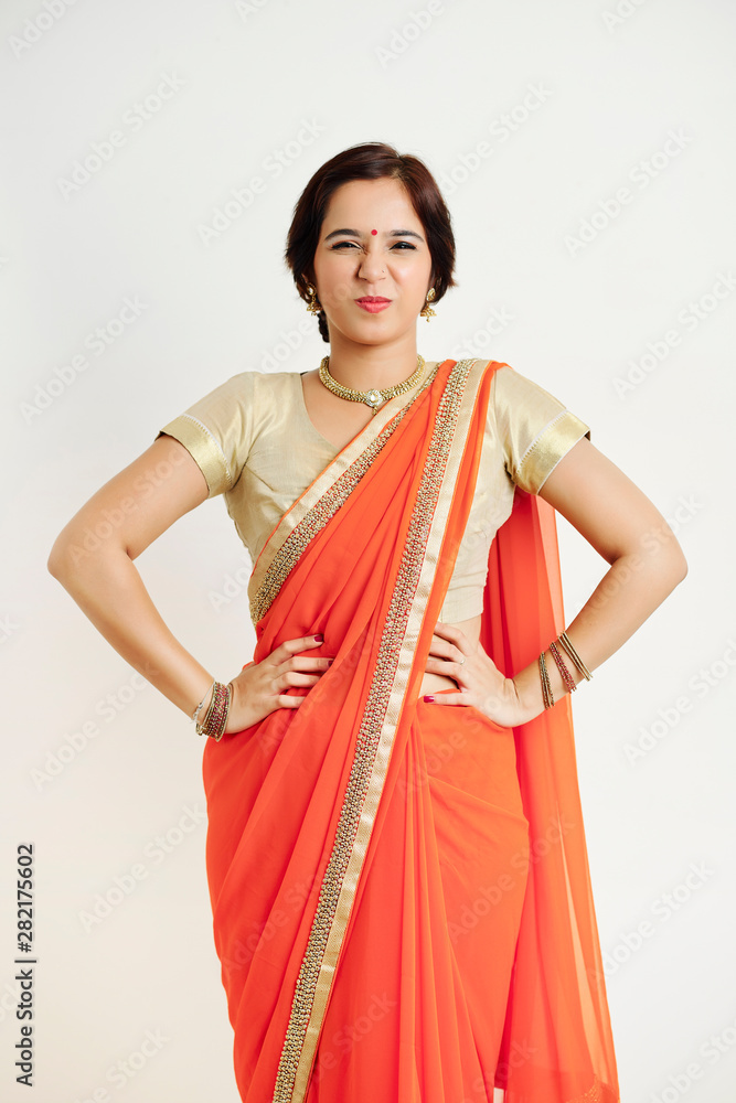 Naughty young Indian woman standing with hands on her hips, squinting her eyes and looking at camera