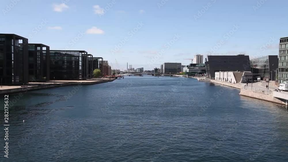 A tilt shot of a view over the channel of Copenhagen, Denmark, with contemporary buildings on each side on a warm sunny day in 2019 A tilt shot of a view over the channel of Copenhagen, Denmark, with contemporary buildings on each side on a warm sunny day in 2019